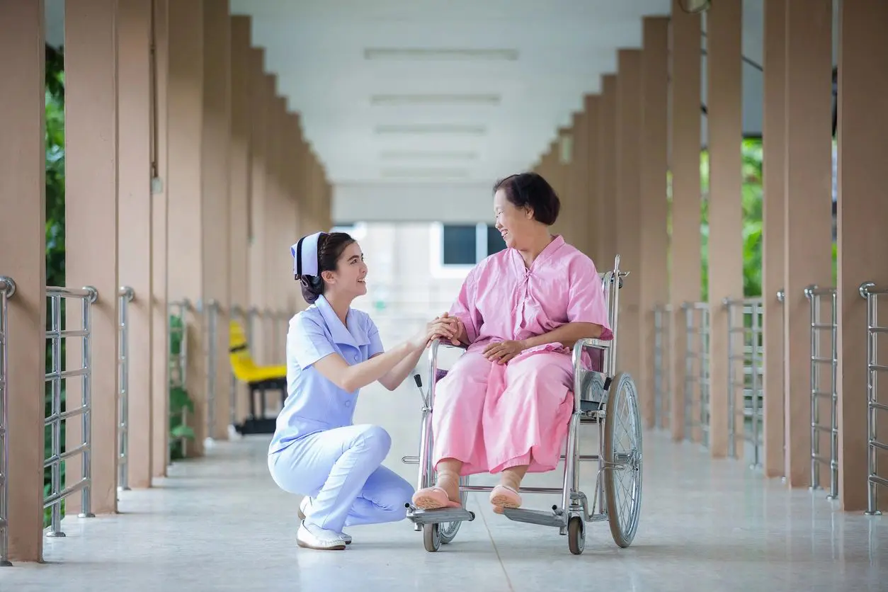 A nurse is helping an elderly woman in a wheelchair.