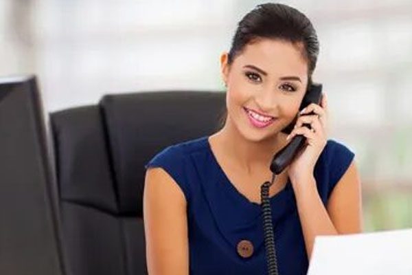 A woman sitting at her desk talking on the phone.