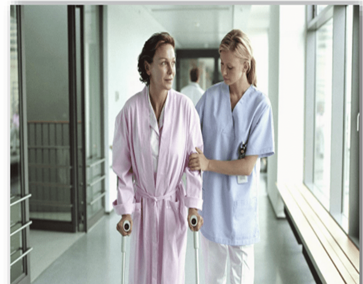 Two women in scrubs are walking down a hallway.