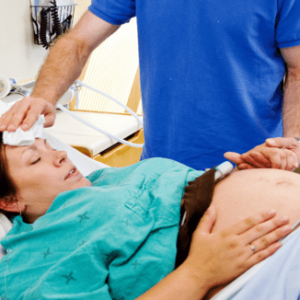 A man is adjusting the head of a pregnant woman.